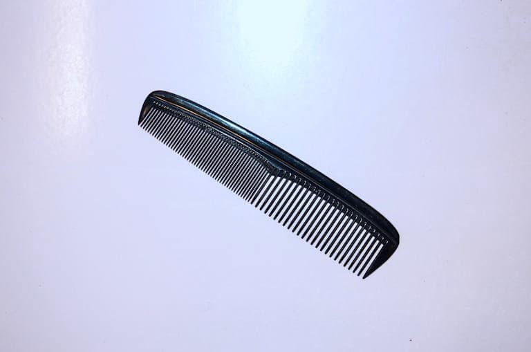 A simple black plastic comb isolated on a white background for hygiene and grooming